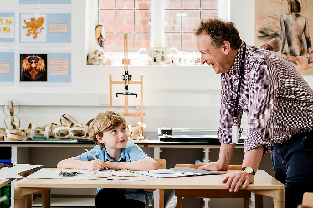 Young Male student in conversation with male teacher in art lesson